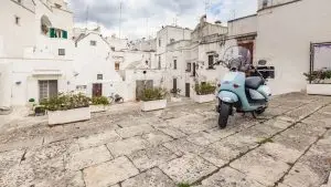 וספה קלאסית חונה בסמטה איטלקית עתיקה - החלום שמפתה תיירים לשקול השכרת קטנוע בנאפולי